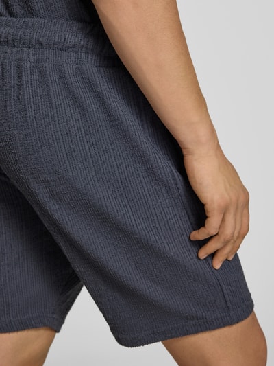 Männermodel trägt Shorts mit Label-Patch Modell 'LIBCO' von Pegador, Material-Mix, Strukturmuster, Elastischer Bund, Detailaufnahme Rückansicht.