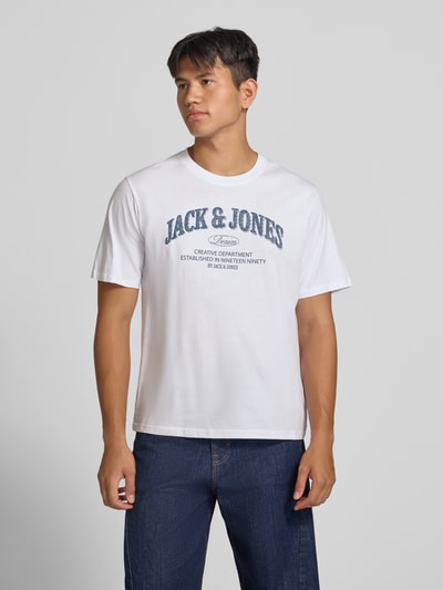 Männermodel trägt Regular Fit T-Shirt aus reiner Baumwolle Modell 'Denver' von JACK & JONES, weiß mit blauem Logo-Print, Ganzkörperansicht von vorne.