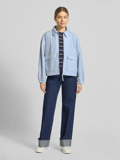 Kobiece model nosi kurtkę Jacke mit Pattentaschen Modell 'CICAMI' od CINQUE w kolorze jasnoniebieskim, krój regular fit, wykładany kołnierz, zamek błyskawiczny, kieszenie z patką; długość tyłu w rozmiarze 36: 58 cm, szerokość ramion w rozmiarze 36: 50 cm, szerokość klatki piersiowej w rozmiarze 36: 56 cm, długość rękawów w rozmiarze 36: 59 cm, całkowity widok z przodu.