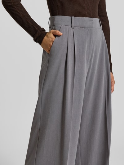Frauenmodel trägt Wide Fit Hose mit Viskose-Anteil von MYON in Grau, elastischer Material-Mix, Bundfalten, Nahaufnahme Oberkörper.