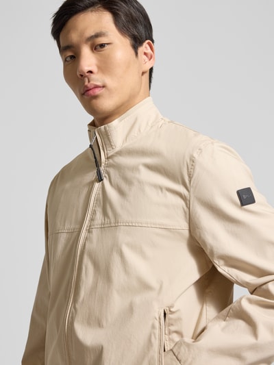 Männermodel trägt Jacke mit Stehkragen Modell 'Calvin' von Brax in Beige, Baumwoll-Mix mit Stretch, Reißverschlusstaschen, Nahaufnahme Oberkörper.