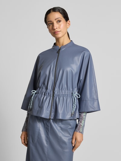 Frauenmodel trägt Blazer in Leder-Optik mit Stehkragen von Marc Cain, taillierte Passform, Reißverschluss, 3/4-Arm, Ganzkörperansicht von vorne.