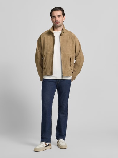 Męski model nosi Regular Fit Lederjacke aus echtem Ziegenleder Modell 'LORIDGE' od HUGO, beżowy welur, patki, kołnierz stójka, widok całej sylwetki z przodu.