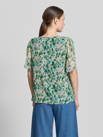 Młody modelka nosi Blusenshirt mit Schlüsselloch-Ausschnitt Modell 'EMMA' od Vila, krój regular fit, kolorowy wzór allover, długość tyłu w rozmiarze 36: 60 cm, długość rękawa w rozmiarze 36: 29 cm, widok całej sylwetki z tyłu