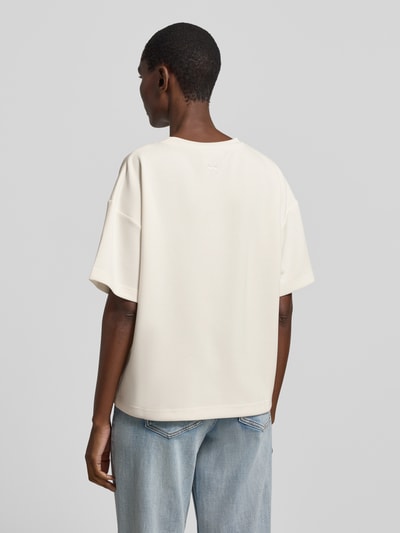 Männermodel trägt T-Shirt mit Rundhalsausschnitt Modell 'Helle' von My Essential Wardrobe, kremowy odcień, boxy fit, materiał z domieszką wiskozy, lekko opuszczone ramiona, widoczne faktury materiału, długość tyłu w rozmiarze XS/S 60 cm, Ganzkörperansicht Rückansicht.