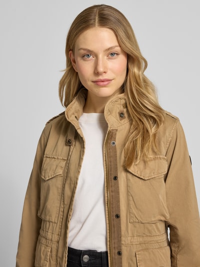 Frauenmodel trägt Jacke mit Pattentaschen Modell 'NORI' von khujo in Beige, Baumwolle mit Stehkragen, Nahaufnahme Oberkörper.