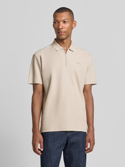 Männermodel trägt beiges Regular Fit Poloshirt aus reiner Baumwolle Modell 'Pe_RibNylon' von BOSS Orange, glatte Struktur, Ganzkörperansicht von vorne.