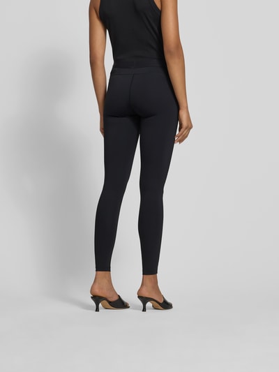 Frauenmodel trägt Leggings mit Label-Detail von black palms aus Elastischer-Material-Mix in Schwarz, enganliegende Passform, Knöchellänge, Ganzkörperansicht Rückansicht.