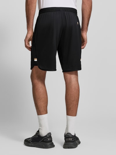 Männermodel trägt Regular Fit Shorts mit Label-Schriftzug Modell 'TOC SPIN 9 INCH' von BOSS Green, unifarben, Rückansicht Ganzkörperansicht.