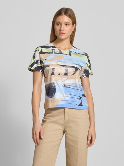 Modelka nosi T-Shirt im Allover-Look mit Rundhalsausschnitt von Betty Barclay, damski t-shirt, mieszanka bawełny i mikromodalu, krój regular fit, wzór na całej powierzchni, okrągły dekolt, długość tyłu w rozmiarze 36: 56 cm, całkowity widok z przodu.