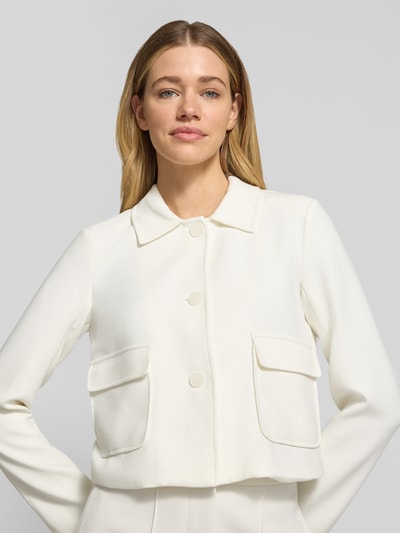 Frauenmodel trägt Blazer mit Pattentaschen Modell 'RITA' von GUIDO MARIA KRETSCHMER WOMAN in Weiß, Material-Mix mit Viskose-Anteil, Kentkragen, Knopfleiste, Gerader-Schnitt, Nahaufnahme Oberkörper.