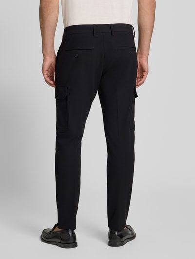 Męski model nosi spodnie z kieszeniami z patką Model 'BJORN' od Antony Morato, czarne, krój skinny fit, widok całej sylwetki z tyłu, Szerokość w rozmiarze 50: 44 cm, Długość wewnętrzna nogawki w rozmiarze 50: 75 cm, kieszenie boczne, kieszenie z patką na rzep, z tyłu kieszeń z wypustką, zapięcie na guzik i zamek błyskawiczny