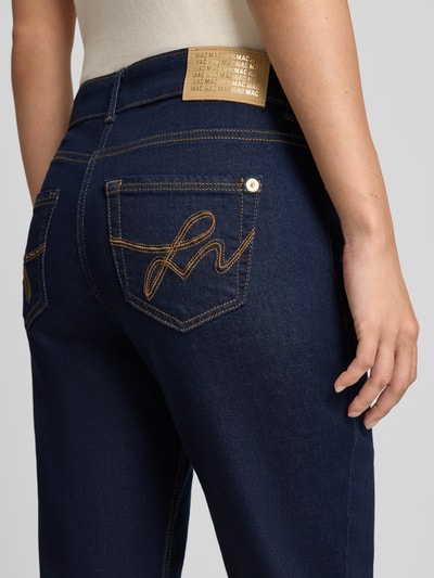 Frauenmodel trägt Straight Fit Jeans aus Baumwoll-Mix Modell 'Carrie' von MAC in Dunkelblau mit gelber Ziernaht, Nahaufnahme Rückansicht, Damen Straight Fit Jeans von MAC.