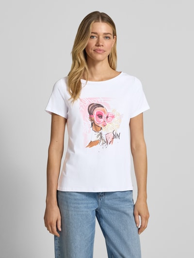 Frauenmodel trägt Regular Fit T-Shirt mit Motiv-Print von More & More in Weiß mit Pailettenbesatz, U-Boot-Ausschnitt, Ganzkörperansicht von vorne.
