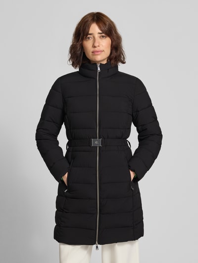 Frauenmodel trägt Taillierter Steppmantel mit Kapuze von Lauren Ralph Lauren in Schwarz mit Gürtel und Reißverschluss, Ganzkörperansicht von vorne.