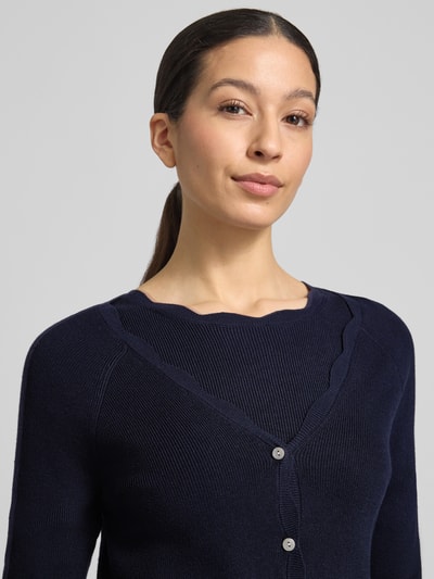 Frauenmodel trägt Strickcardigan aus Viskose-Mix von Christian Berg Woman in Dunkelblau, tailliert, Knopfleiste, Rüschen, Nahaufnahme Oberkörper