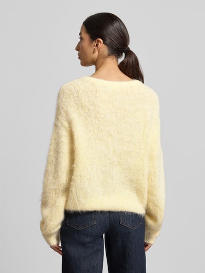 Modelka nosi Strickpullover mit gerippten Abschlüssen Modell 'NIBY' od American Vintage, jasny żółty, luźny krój, dzianina alpaka mix, widok całej sylwetki od tyłu