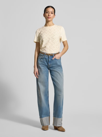 Kobiece modelka nosi Regular Fit T-Shirt mit Viskose-Anteil od comma, damski t-shirt z mieszanki materiałów z dodatkiem wiskozy, krój regular fit, ozdobne obszycie, okrągły dekolt, długość tyłu w rozmiarze 36: 55 cm, jasny beż, błękitne jeansy, całkowity widok z przodu.