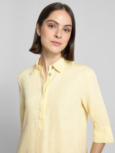 Frauenmodel trägt knielanges Hemdblusenkleid aus Leinen mit 3/4-Arm von Christian Berg Woman in zartem Gelb, Nahaufnahme Oberkörper. A-Linie, Hemdblusenkragen und verdeckte Knopfleiste, strukturierte Leinentextur.