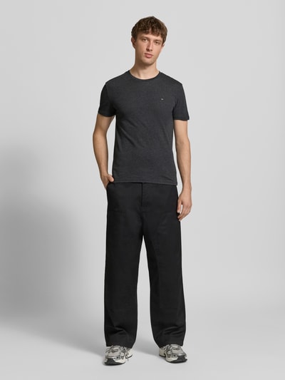 Männermodel trägt Slim Fit T-Shirt aus Baumwoll-Mix Modell 'JASPE HERITAGE' von Tommy Jeans in Melange-Optik mit Logo-Stitching, Ganzkörperansicht von vorne
