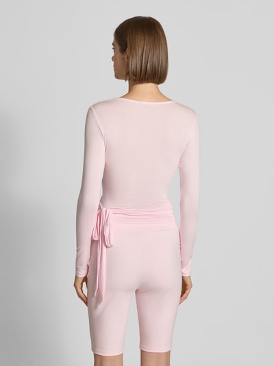 Frauenmodel trägt Cardigan in Wickel-Optik Modell 'Luca' von OH APRIL in zartem Rosa, feine Textur, Modal-Elasthan-Mix, Ganzkörperansicht Rückansicht.