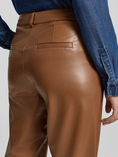 Frauenmodel trägt Flared Fit Stoffhose in Leder-Optik von MORE & MORE, glatte braune Oberfläche, Detailaufnahme Rückansicht.