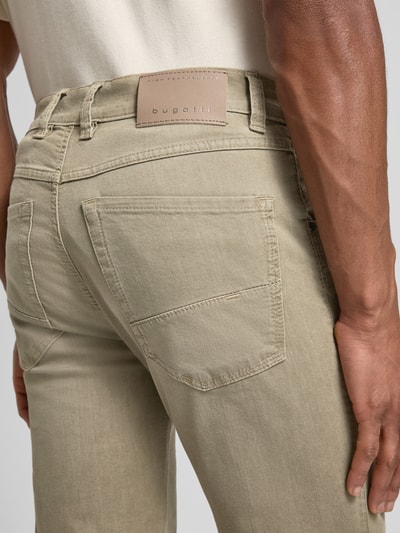 Męski model nosi Regular Fit Jeans mit Eingrifftaschen von bugatti, beżowy bawełniany mix ze stretchem, detal tylnej kieszeni, zbliżenie. Szerokość w rozmiarze 32/32: 44 cm, długość nogawki wewnętrznej 80 cm.