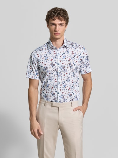 Männermodel trägt Regular Fit Business-Hemd aus Baumwolle mit Kentkragen von Christian Berg Men mit Allover-Look, Ganzkörperansicht von vorne. Rückenlänge 78 cm, Schulterbreite 47 cm, Ärmellänge 23 cm bei Größe 39/40. Hemd in Weiß mit mehrfarbigen floralen Mustern, glatte Textur.