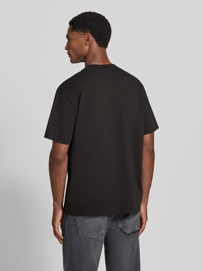 Männermodel trägt Regular Fit T-Shirt aus reiner Baumwolle von Lacoste in Schwarz, dezente Struktur, Ganzkörperansicht Rückansicht.