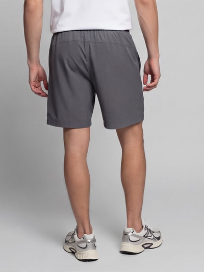 Männermodel trägt Regular Fit Sportshorts mit Logo-Print von Under Armour, Herren Sportshorts, grau, glatte Textur, Ganzkörperansicht Rückansicht.