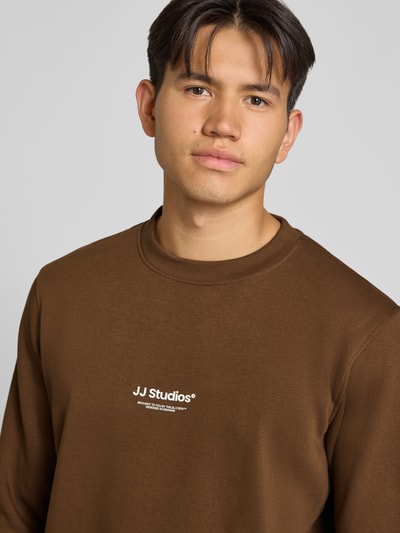 Männermodel trägt Regular Fit Sweatshirt aus katoenmix Model 'Soho' van JACK & JONES met logoprint, ronde hals, detailaufnahme bovenlichaam.