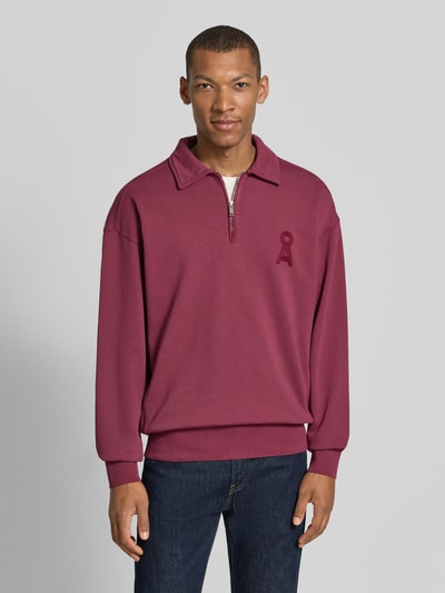 Männermodel trägt bordeauxroten Relaxed Fit Troyer aus reiner Baumwolle Modell 'ICONIC Å GMT' von ARMEDANGELS, Ganzkörperansicht von vorne.