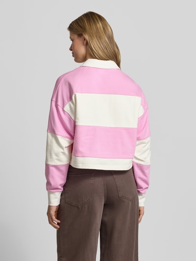 Frauenmodel trägt Relaxed Fit Sweatshirt aus reiner Baumwolle von Marc O'Polo Denim, Optik:Allover-Muster, gestreift, Cropped, Polokragen, Ärmelabschluss gerippt, Farbe Rosa und Creme, Struktur weich, Ganzkörperansicht Rückansicht.