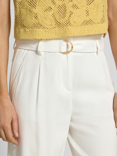 Frauenmodel trägt Culotte aus Viskose mit Gürtel von Christian Berg Woman, weiße Wide-Fit Hose mit Biesen, französische Eingrifftaschen, Nahaufnahme Oberkörper.