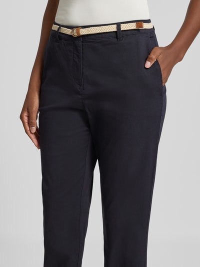Frauenmodel trägt Chino mit Gürtel und Gesäßtaschen von Christian Berg Woman aus Baumwoll-Elasthan-Mix in Dunkelblau, Nahaufnahme Oberkörper.
