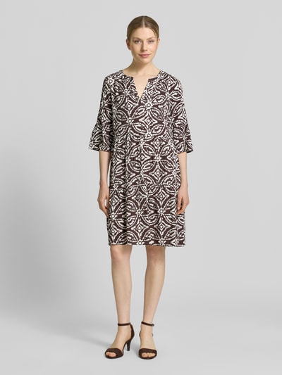 Frauenmodel trägt Regular Fit Minikleid aus reiner Viskose mit Kachel-Print von Christian Berg Woman Selection, taillierte Passform, Tunika-Ausschnitt, Halbarm, Farbmix Braun und Weiß, klare Muster, weiche Textur, Rückenlänge 89 cm, Brustweite 46 cm, Ärmellänge 39 cm, Ganzkörperansicht von vorne.