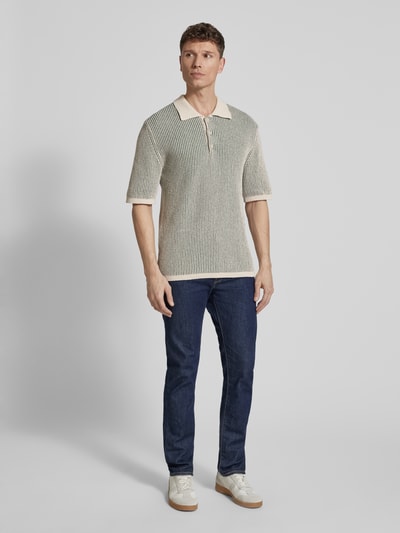 Męski model nosi Slim Fit Poloshirt aus Baumwoll-Mix model 'Elwo' von Wood Wood, imitacja dzianiny, prążkowane wykończenia, krój slim fit, długość tyłu w rozmiarze M: 72 cm, widok całej sylwetki z przodu.