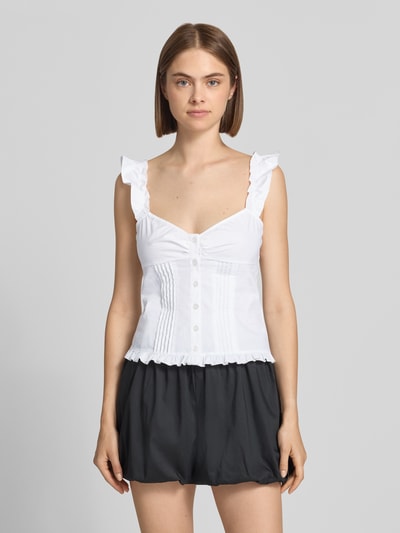 Frauenmodel trägt Slim Fit Bluse mit Rüschenbesatz von Gina Tricot, weiße Farbe, Knopfleiste, Spaghetti-Träger, Ganzkörperansicht von vorne.