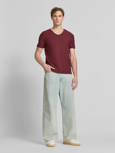 Męski model nosi T-Shirt mit V-Ausschnitt und Rollsaum von MCNEAL, krój regular fit, bawełna, dekolt w serek, długość tyłu 81 cm, Ganzkörperansicht von vorne.