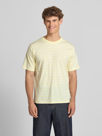 Männermodel trägt T-Shirt mit Streifenmuster und Label-Stitching von Jack & Jones in Gelb, Reine Baumwolle, Relaxed-Fit, Rundhalsausschnitt, Rückenlänge bei Größe M 72 cm, Ganzkörperansicht von vorne.