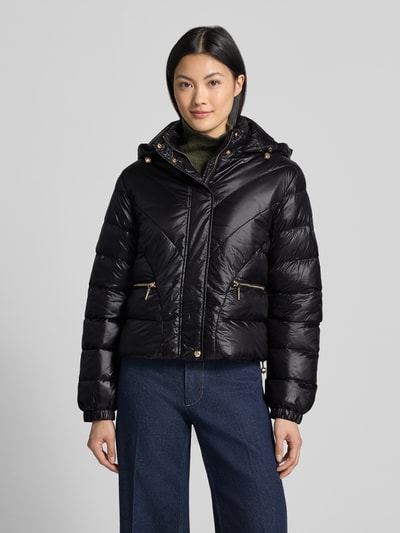 Frauenmodel trägt schwarze Regular Fit Jacke in Stepp-Optik Modell 'IMBOTTITO' von Liu Jo mit Kapuze, Ganzkörperansicht von vorne. Damen Jacke mit Tunnelzugkapuze, Reißverschlusstaschen und glänzender Textur, Rückenlänge 54 cm, Schulterbreite 43 cm, Brustweite 53 cm, Ärmellänge 63 cm, Ganzkörperansicht von vorne.