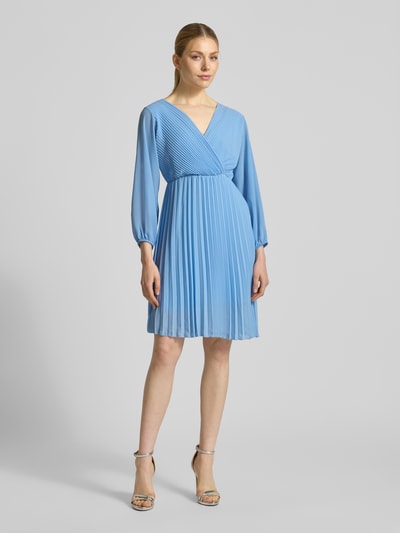 Frauenmodel trägt Knielanges Kleid mit Plisseefalten Modell 'Im44sa' von ZABAIONE in Wickel-Optik, taillierter Schnitt, hellblau, Ganzkörperansicht von vorne. Rückenlänge bei Größe S: 90 cm, Brustweite: 38 cm, Ärmellänge: 52 cm.