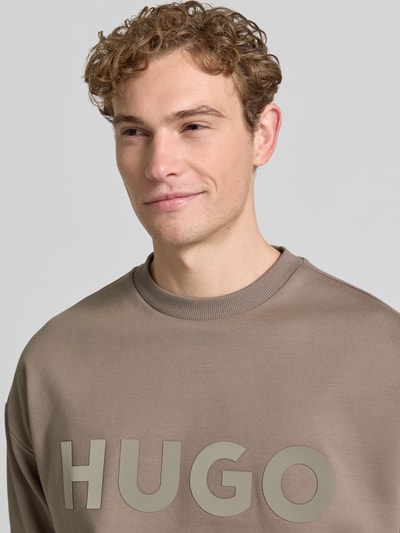 Männermodel trägt Oversized Sweatshirt aus reiner Baumwolle Modell 'DINEX' von HUGO in Optik: Unifarben mit Label-Print, Nahaufnahme Oberkörper.