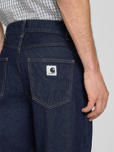 Männermodel trägt Wide Fit jeans uit puur katoen Model "Brandon" van Carhartt Work In Progress, 5-pocketmodel, riemlussen, knoop- en ritssluiting, bandwijdte maat S 41 cm, binnenbeenlengte maat S 73 cm, detailaufnahme rug, KI-modifiziertes Bild