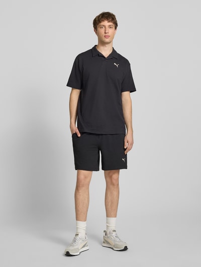 Männermodel trägt Regular Fit T-Shirt mit Logo-Stitching von PUMA PERFORMANCE, schwarzer Baumwoll-Mix mit Stretch-Anteil, Strukturmuster, Reverskragen, Rückenlänge bei Größe M 74 cm, Ganzkörperansicht von vorne.