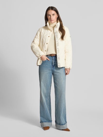 Kobiece modelka nosi Regular Fit Steppjacke mit gefüttertem Stehkragen von Christian Berg Woman Selection, kremowa kurtka pikowana, z efektem pikowania, krój regular fit, stójka z ociepleniem, wpuszczane kieszenie, listwa guzikowa, długość tyłu w rozmiarze 36: 62 cm, szerokość ramion w rozmiarze 36: 41 cm, szerokość w rozmiarze 36: 52 cm, długość rękawów w rozmiarze 36: 62 cm, całkowity widok z przodu