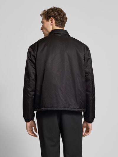 Männermodel trägt Regular Fit Blouson mit Logo-Muster Modell 'H-CRESTELL' von BOSS in Schwarz mit Allover-Muster, Ganzkörperansicht Rückansicht.