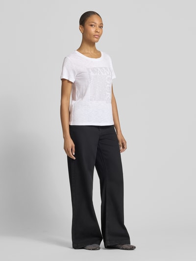 Frauenmodel trägt T-Shirt mit Ziersteinbesatz und Rundhalsausschnitt von monari, weiß, Regular Fit, Baumwoll-Micromodal-Mix, Ganzkörperansicht von vorne.