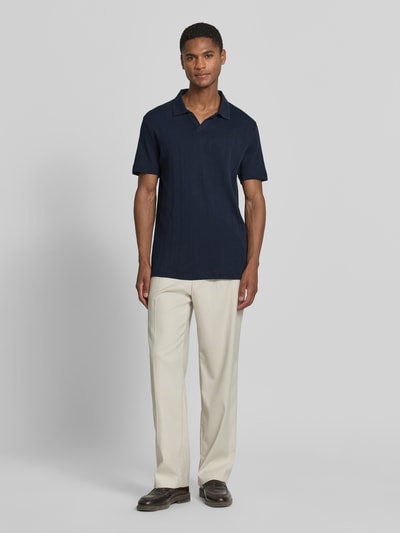 Männermodel trägt Regular Fit Poloshirt in Jaquard-Strick von Lindbergh, Reine Baumwolle, Polokragen, V-Ausschnitt, Label-Detail, Ganzkörperansicht von vorne.