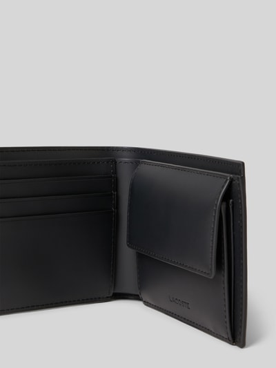 Produktfoto, Portemonnaie mit Allover-Muster Modell 'Noir Gris' von Lacoste in Dunkelgrau mit Logo-Applikation aus Kunstleder, rechteckig, Kartenfächer, Münzfach und Geldscheinfach, Anhänger im Logo-Design, glatte Oberfläche